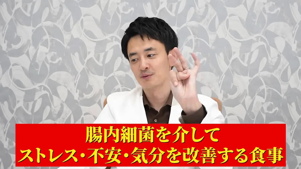 白衣の男性が手を上げてポイントを解説している様子