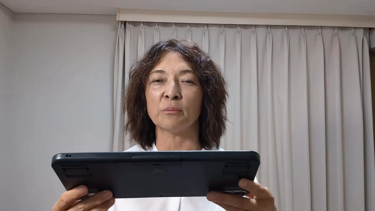 キーボードの背面をカメラに向けて持ち上げている人物