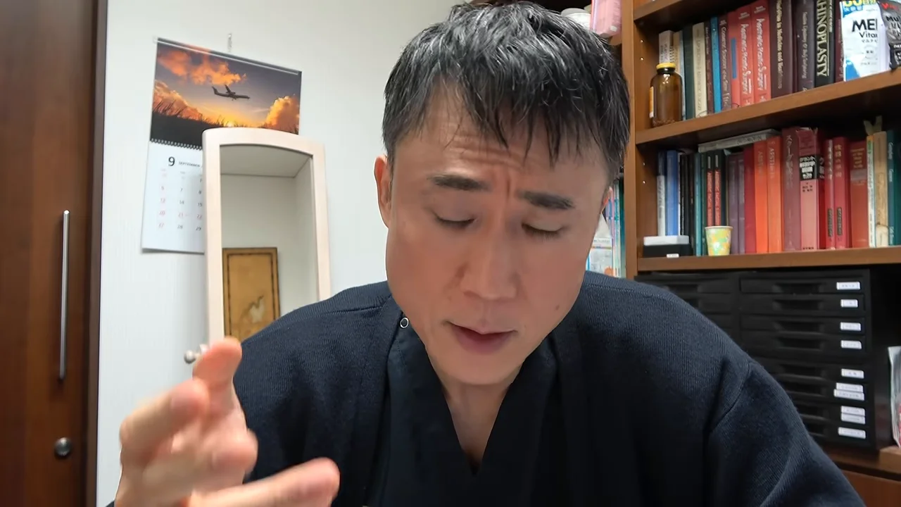 本棚の前に座る男性が手振りを交えながら語っている様子