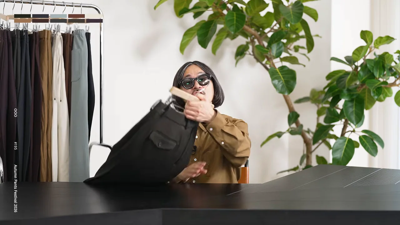 男性が黒いパンツが掛けられたハンガーを机の上に置こうとしている。