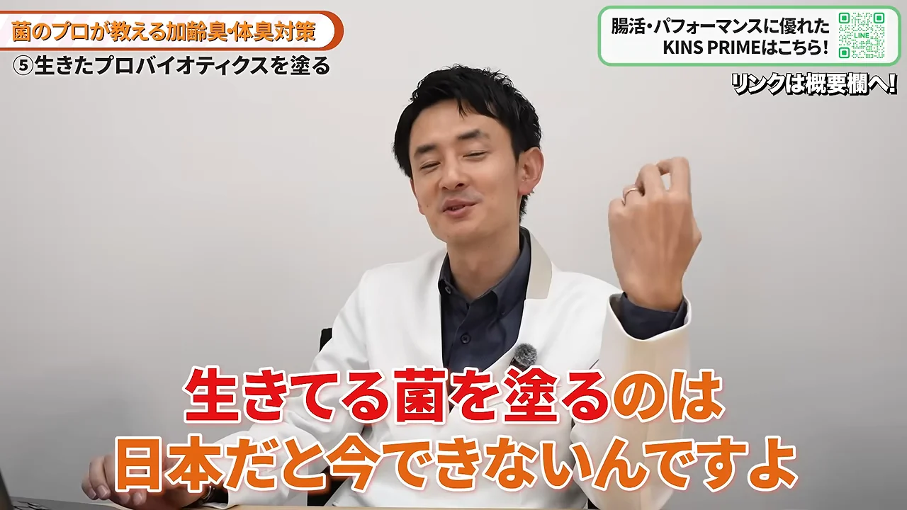 白衣を着た男性が左手を掲げながらカメラに向かって語りかけている場面。