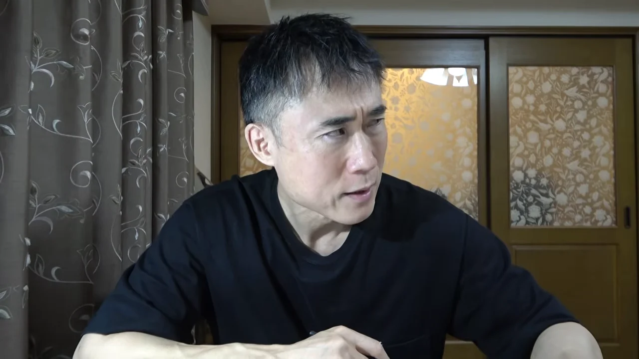 黒い服を着た男性が視線を横に向けて話している様子。