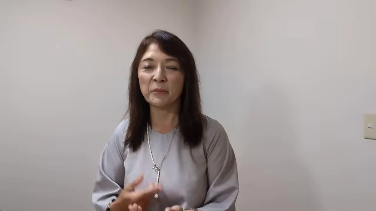 女性が手を動かしてジェスチャーを交えながら語りかけている。