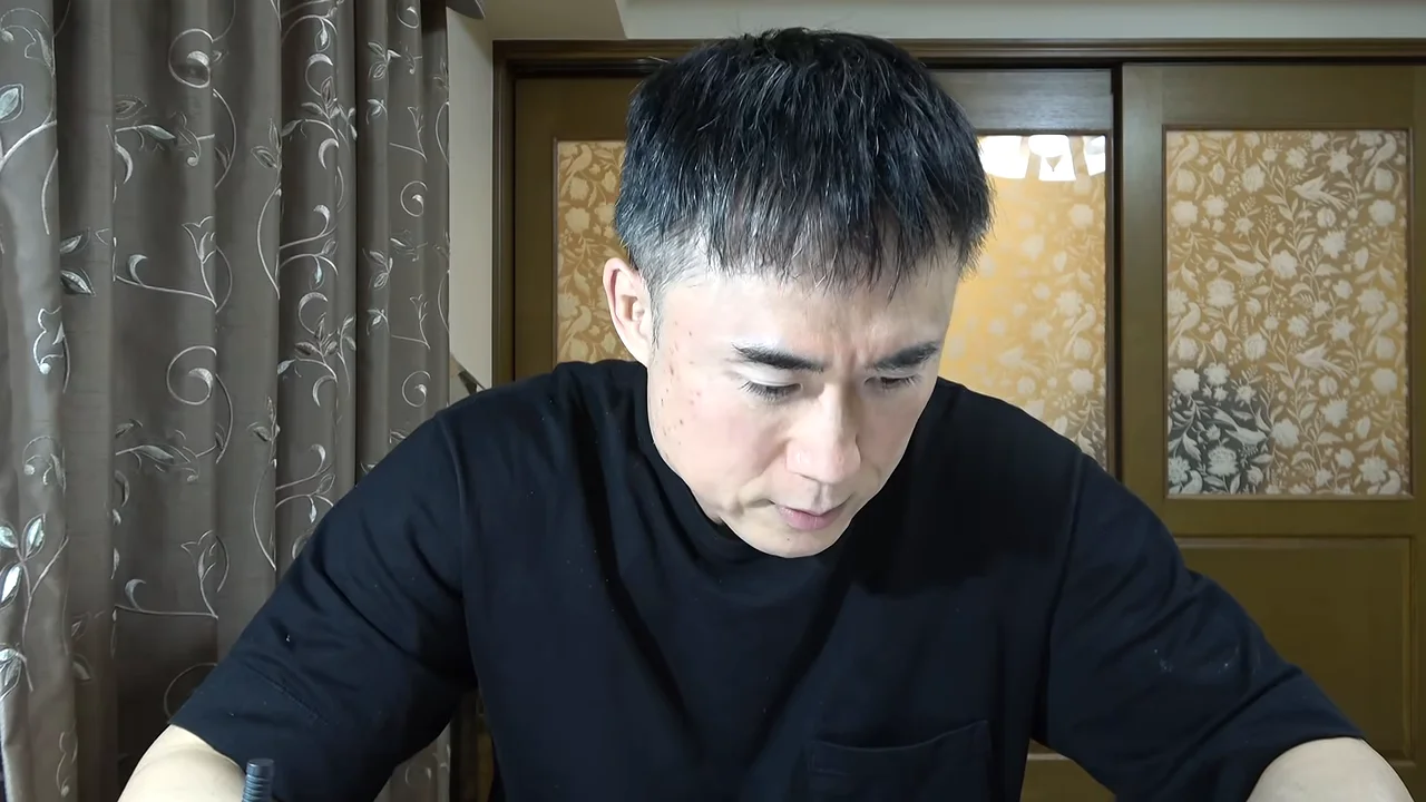 うつむき加減で話す黒いシャツの男性