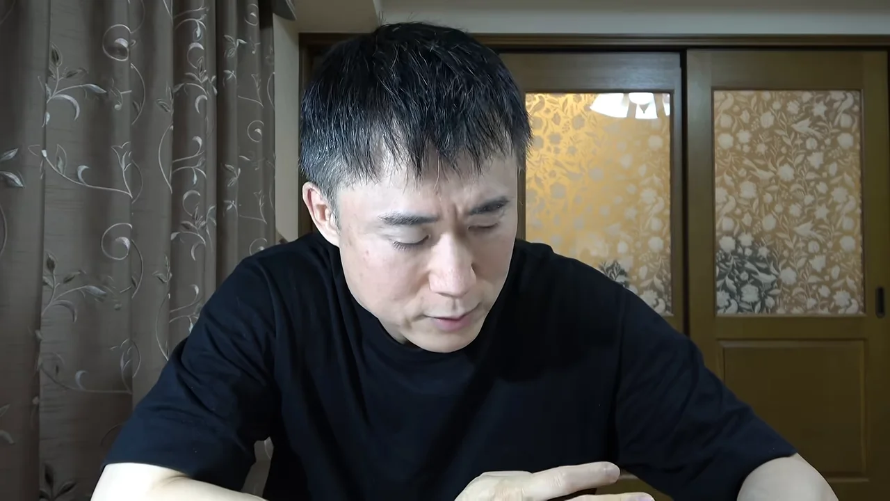手元を見つめながら話す男性。