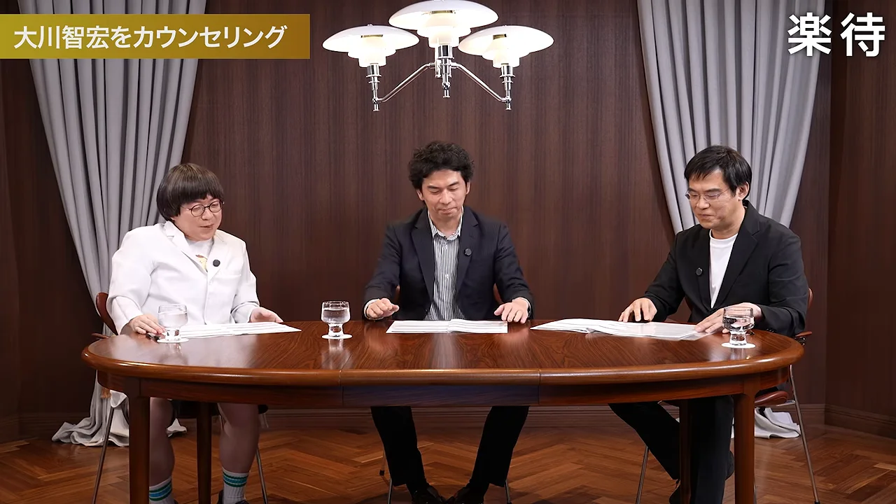 3人の男性が丸い木製テーブルに座り、机の上の資料を見ています。
