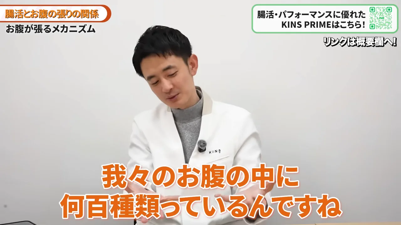 白衣を着た男性が身振り手振りを交えて話しています。