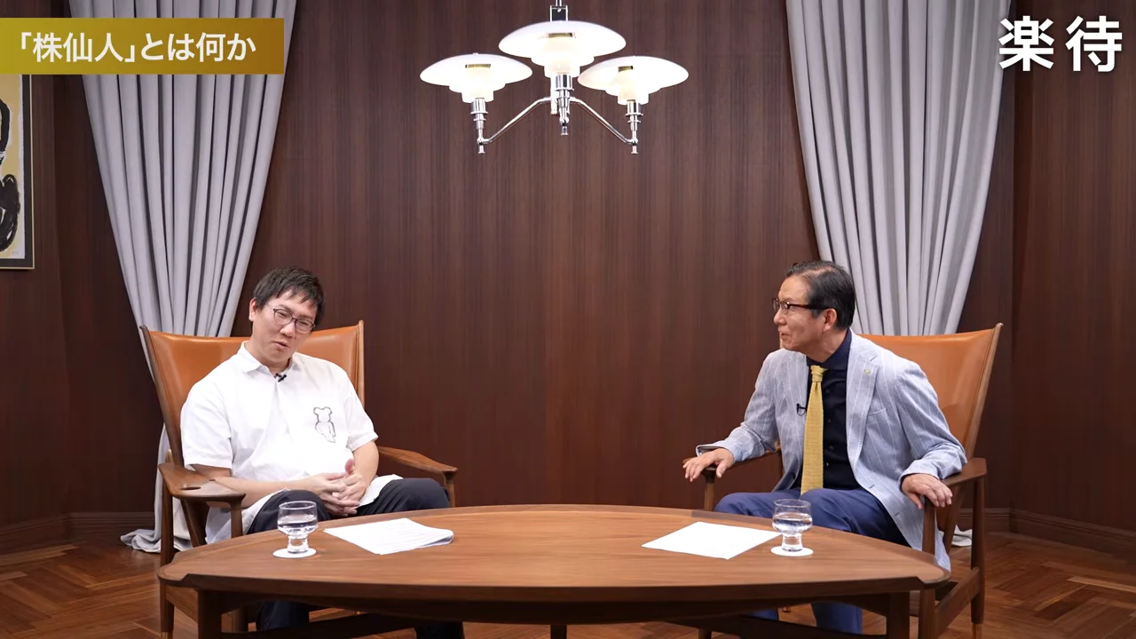 テーブルを挟んで2人の男性が座って対談している様子