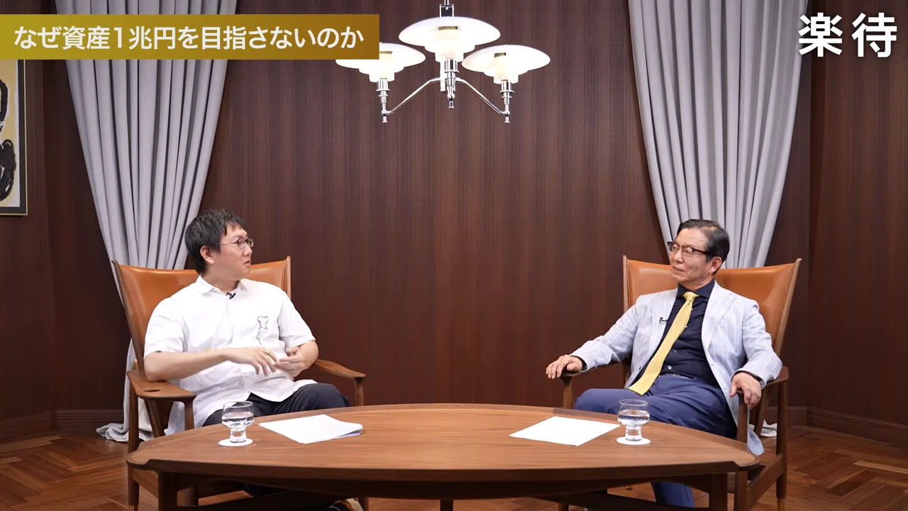 テーブルを囲んで座る2人の男性が話をしている様子