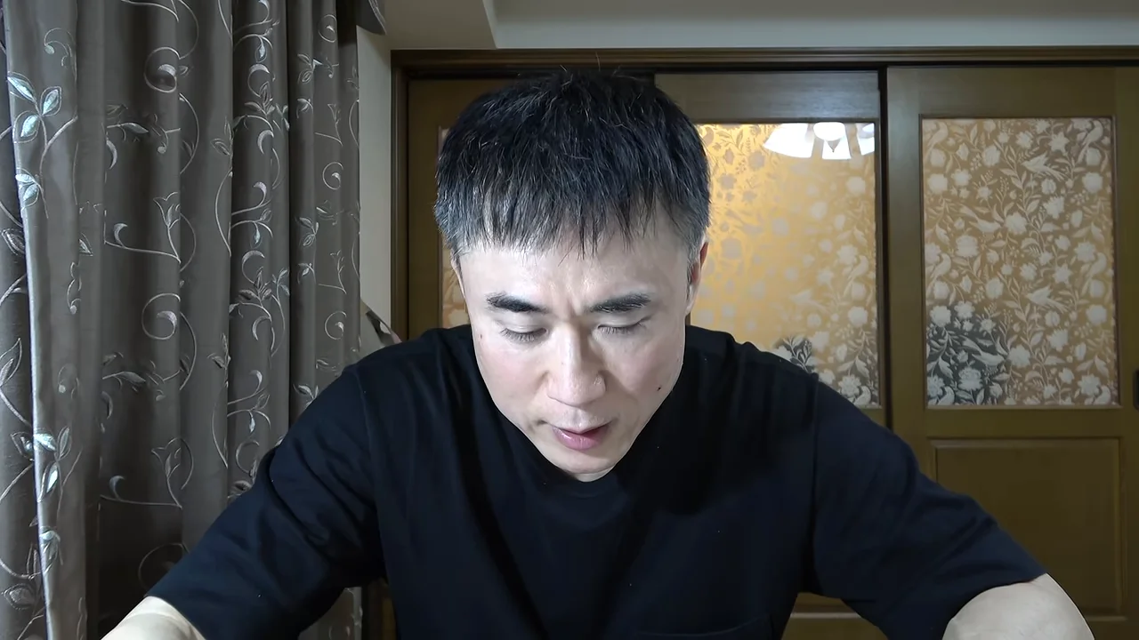 黒いTシャツを着た男性が視線を落としながら話している。