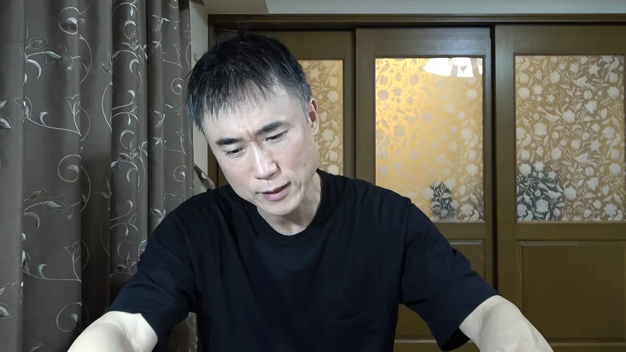 黒いTシャツを着た男性が視線を落として話している様子。