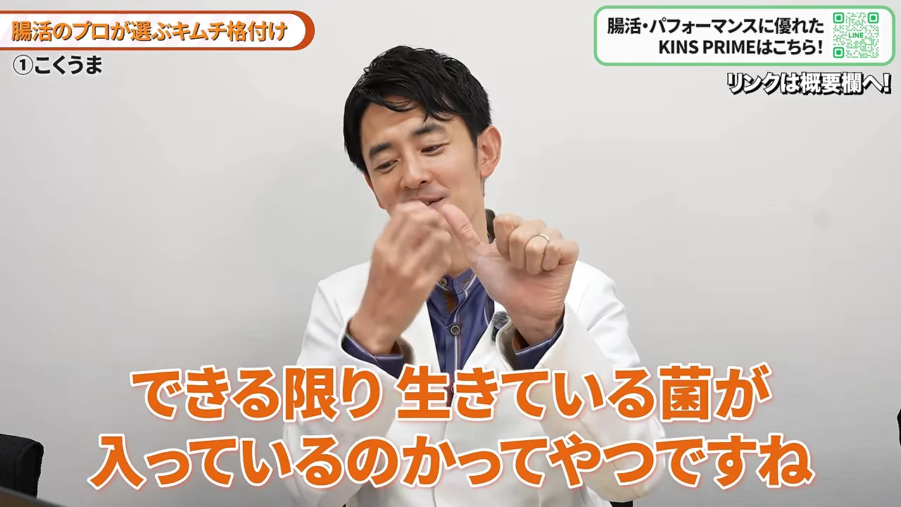 白衣を着た男性が身振り手振りを交えながらキムチの選び方について解説している様子。