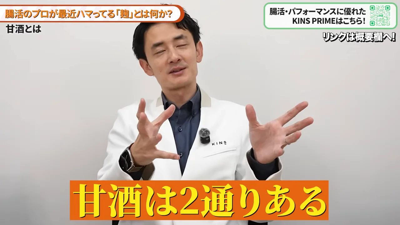 白衣を着た男性が両手を広げて身振り手振りを交えながら話している様子。
