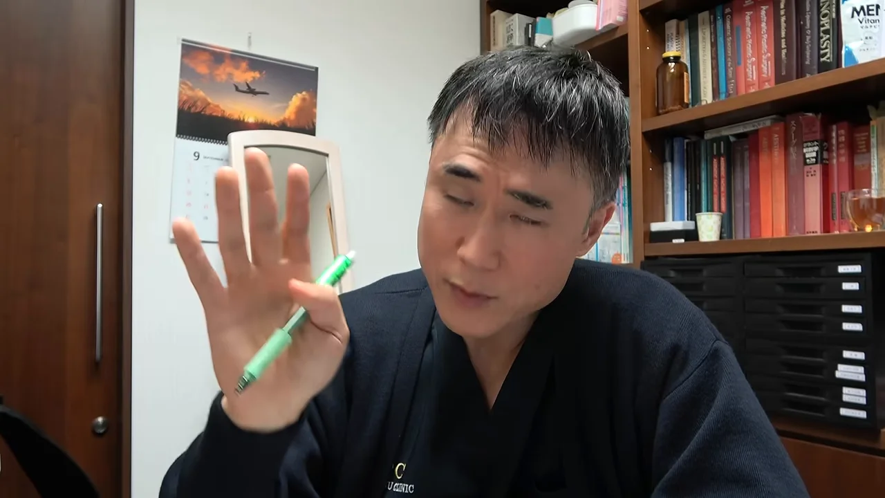 男性がペンを持った右手を広げて掲げながら、斜め前を向いて語っている様子。