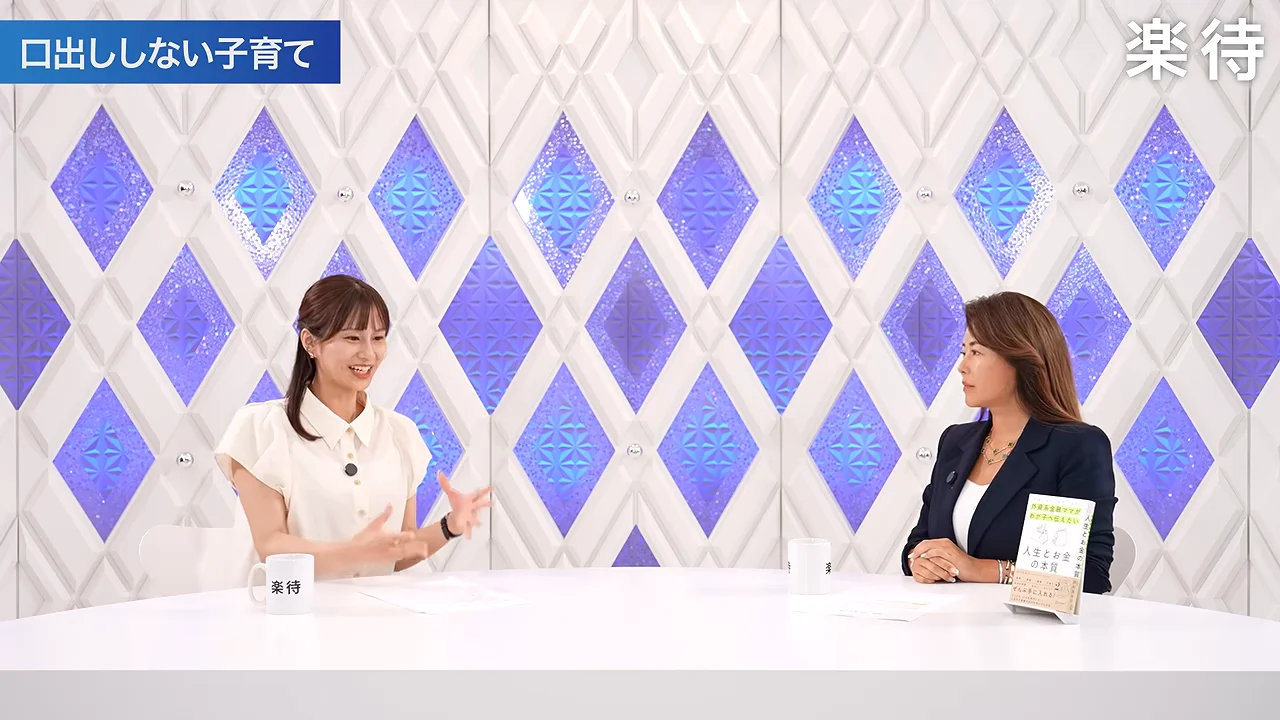 白い服の女性が身振りを交えながら隣の女性と話しています。