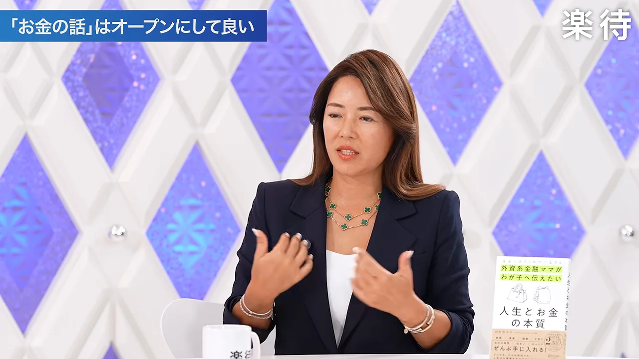ジャケットを着た女性が両手を動かしながら話しています。