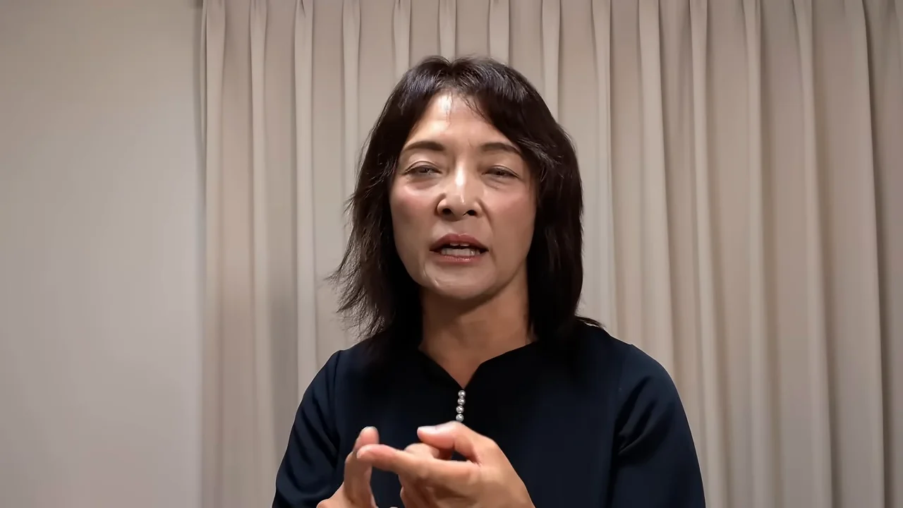 手元で指を組みながら真剣な表情で話す女性のクローズアップショット。