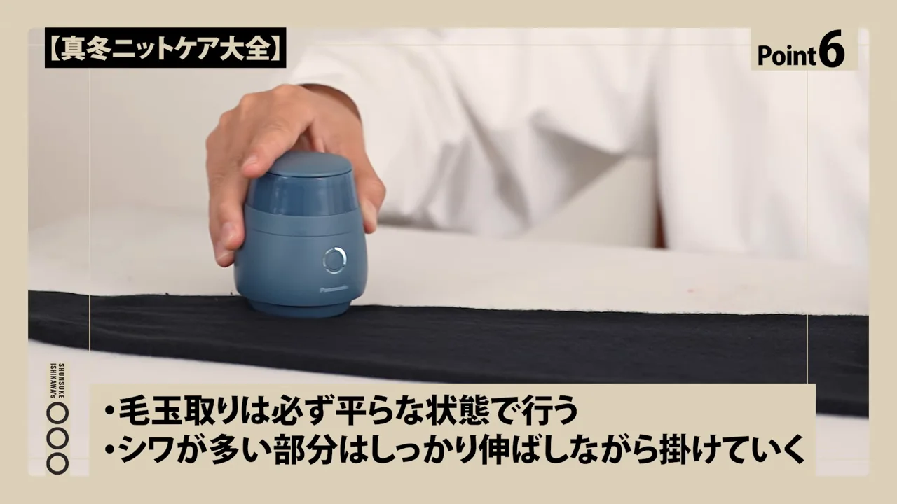 伸ばした黒い衣類の上で電動の毛玉取り機を動かす様子