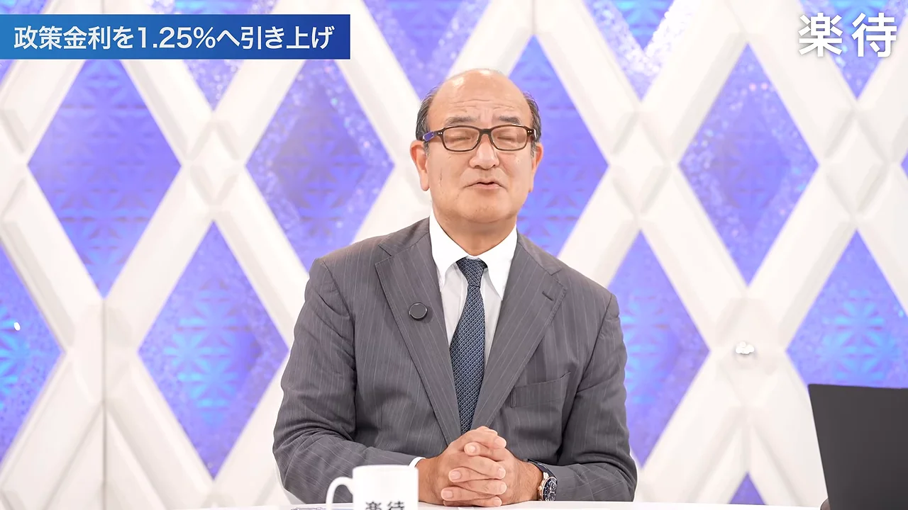 眼鏡をかけスーツを着た男性が手を組んで話している様子。