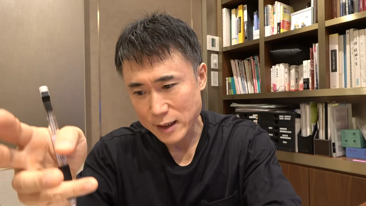 男性がペンを手に持ち、視線を向けている。