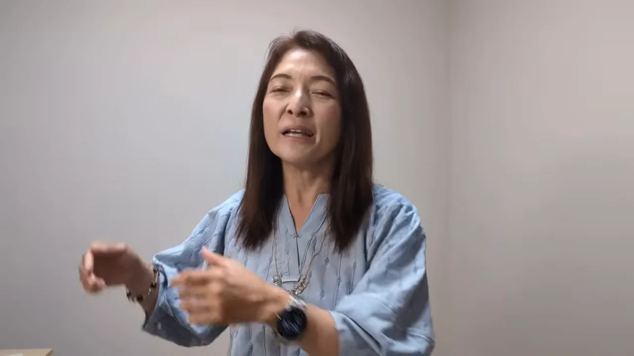 両手を動かしながら話す女性の姿が映し出されています。