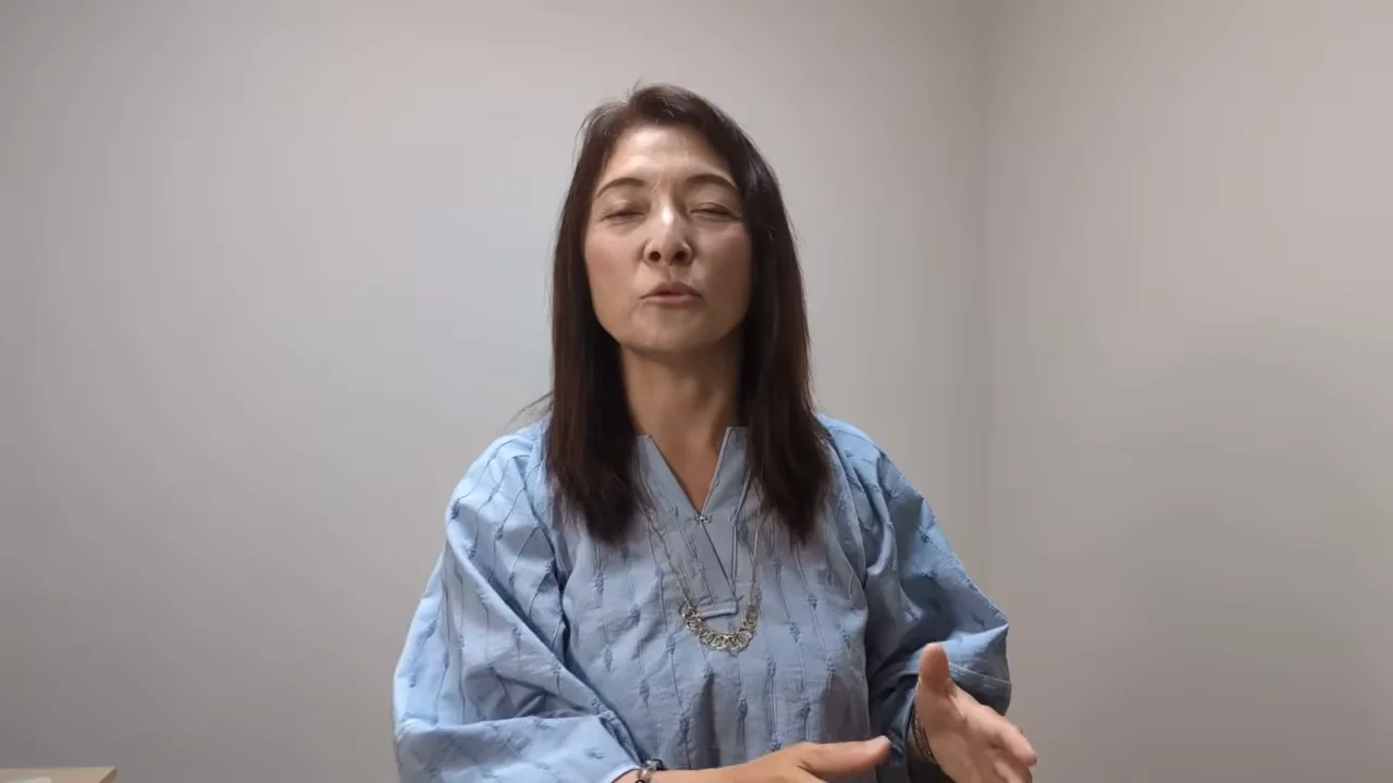 女性が手を前に出しながらカメラに向かって説明しています。