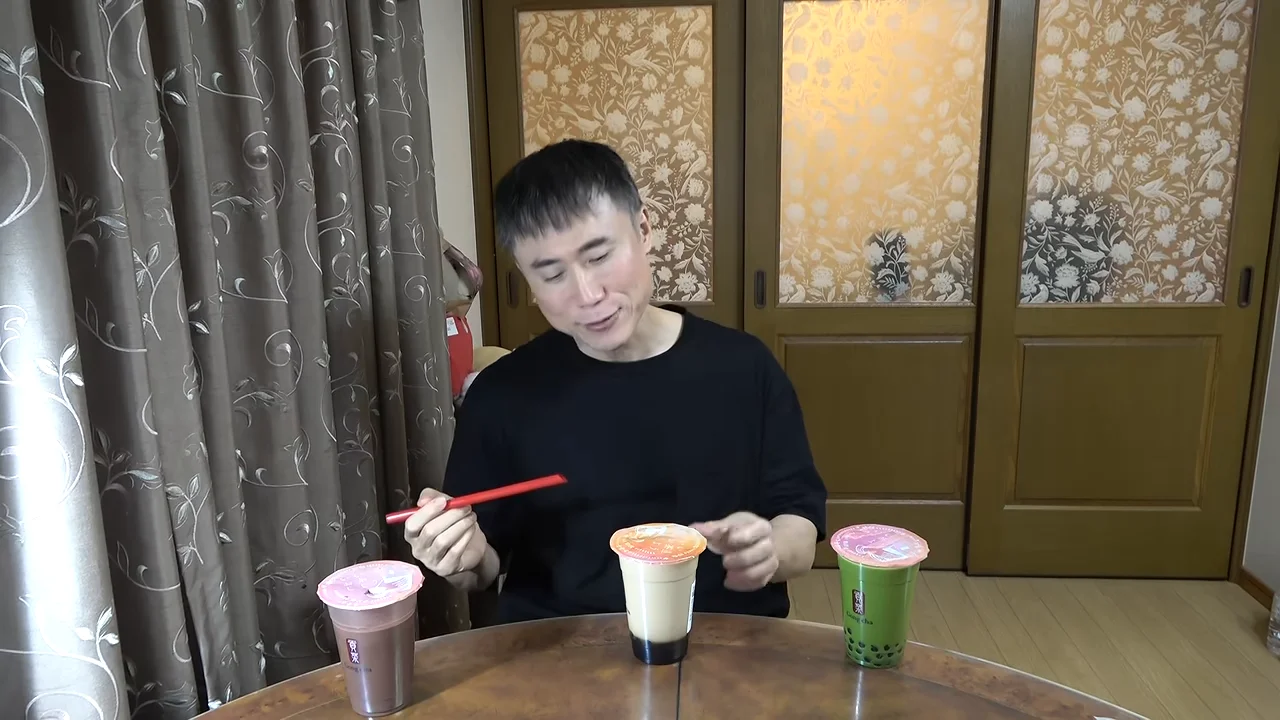 男性が手にしたストローをカップに向けながら説明している様子。