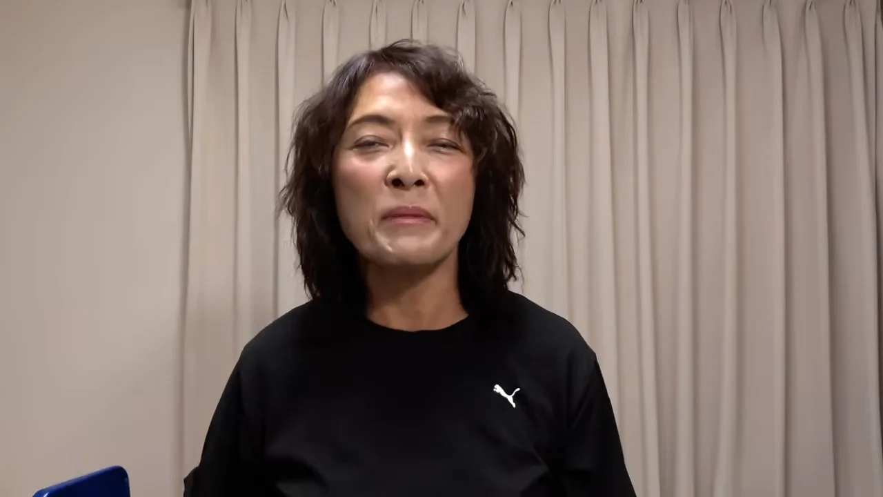 カーテンを背景にカメラを見つめて正面を向いている女性。