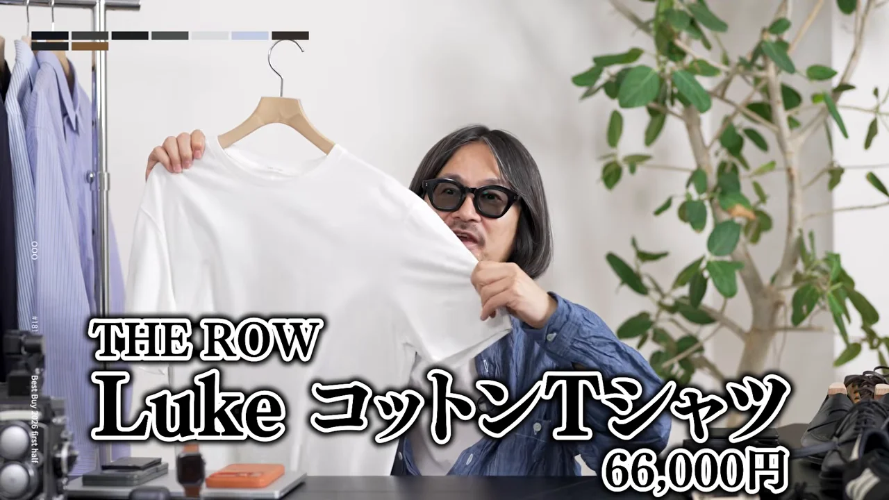 男性が白いシャツを両手で広げて見せており、画面下部に大きな文字が重なっている。