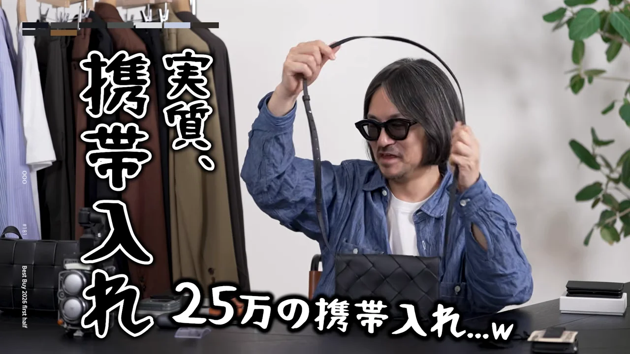 男性が黒いバッグのストラップを持ち上げ、テーブル上のバッグを見せている。