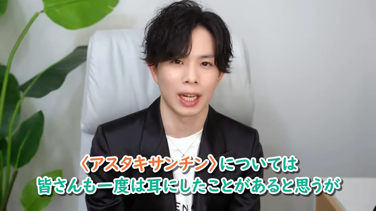 黒いジャケットを着た男性が白い椅子に座って話しています。