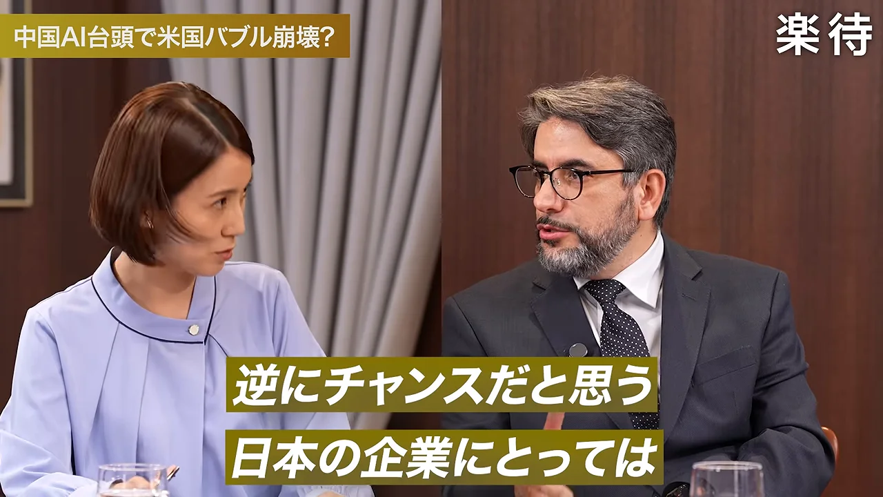 青い服を着た女性と眼鏡をかけたスーツ姿の男性が対談している。