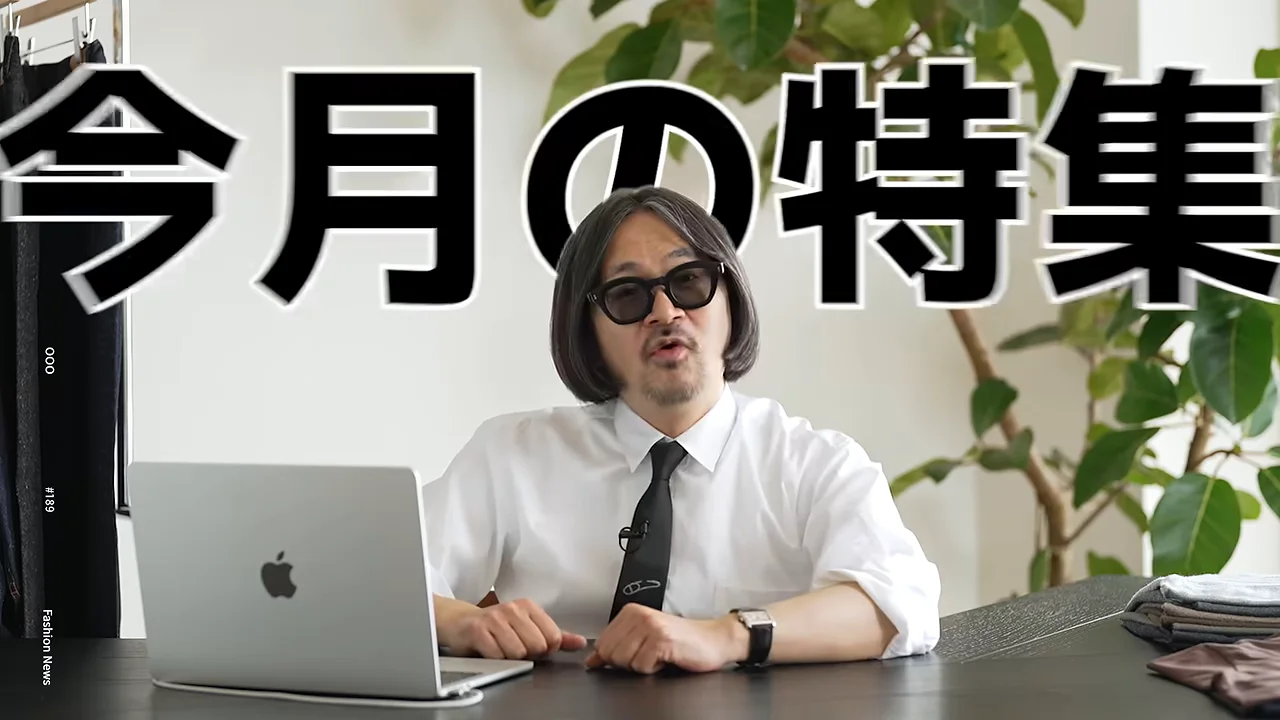 机の前に座る男性の頭上に「今月の特集」という大きなテロップが表示されています。