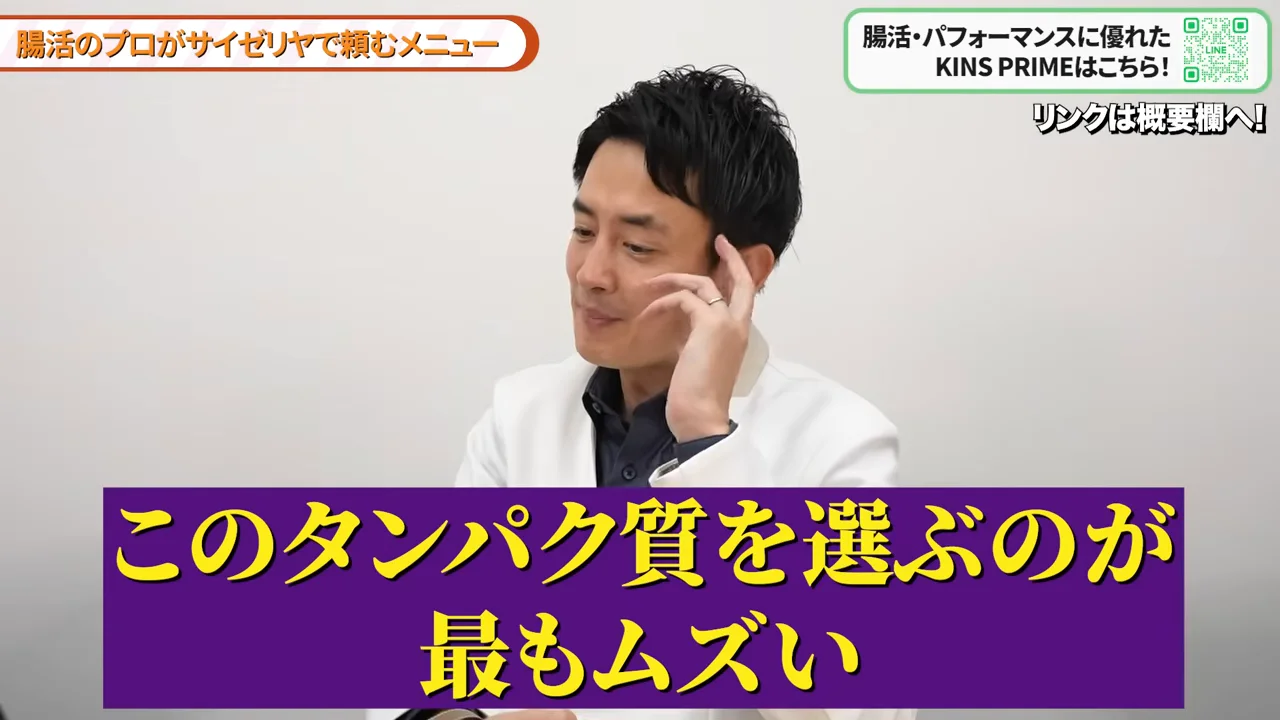 白衣を着た男性がこめかみに手を当てながら話しており、下部にテロップが表示されています。