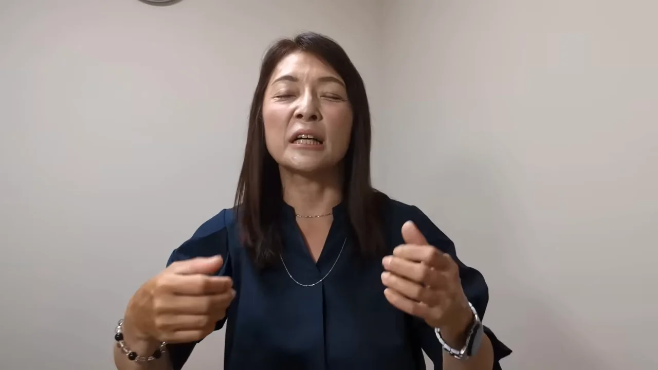 カメラに向かって両手を動かしながら話す女性の姿