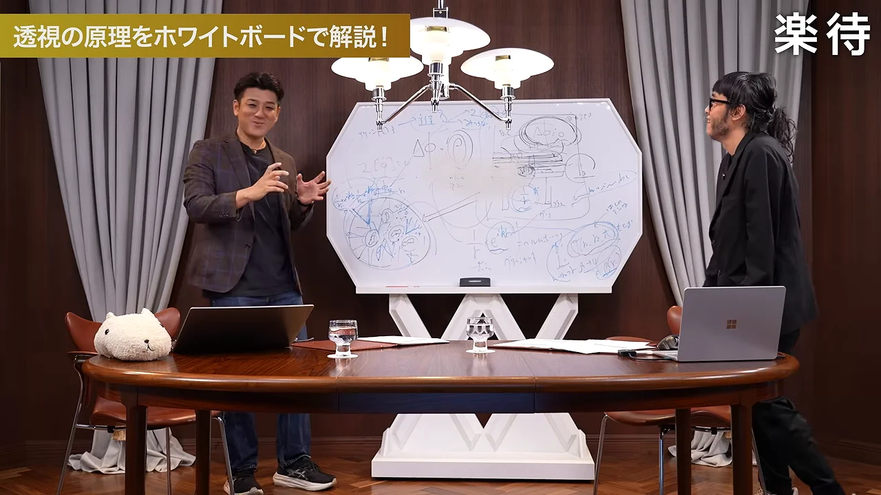 図や文字が描かれた大きなボードを挟み、二人の男性がテーブル越しに向き合っている。