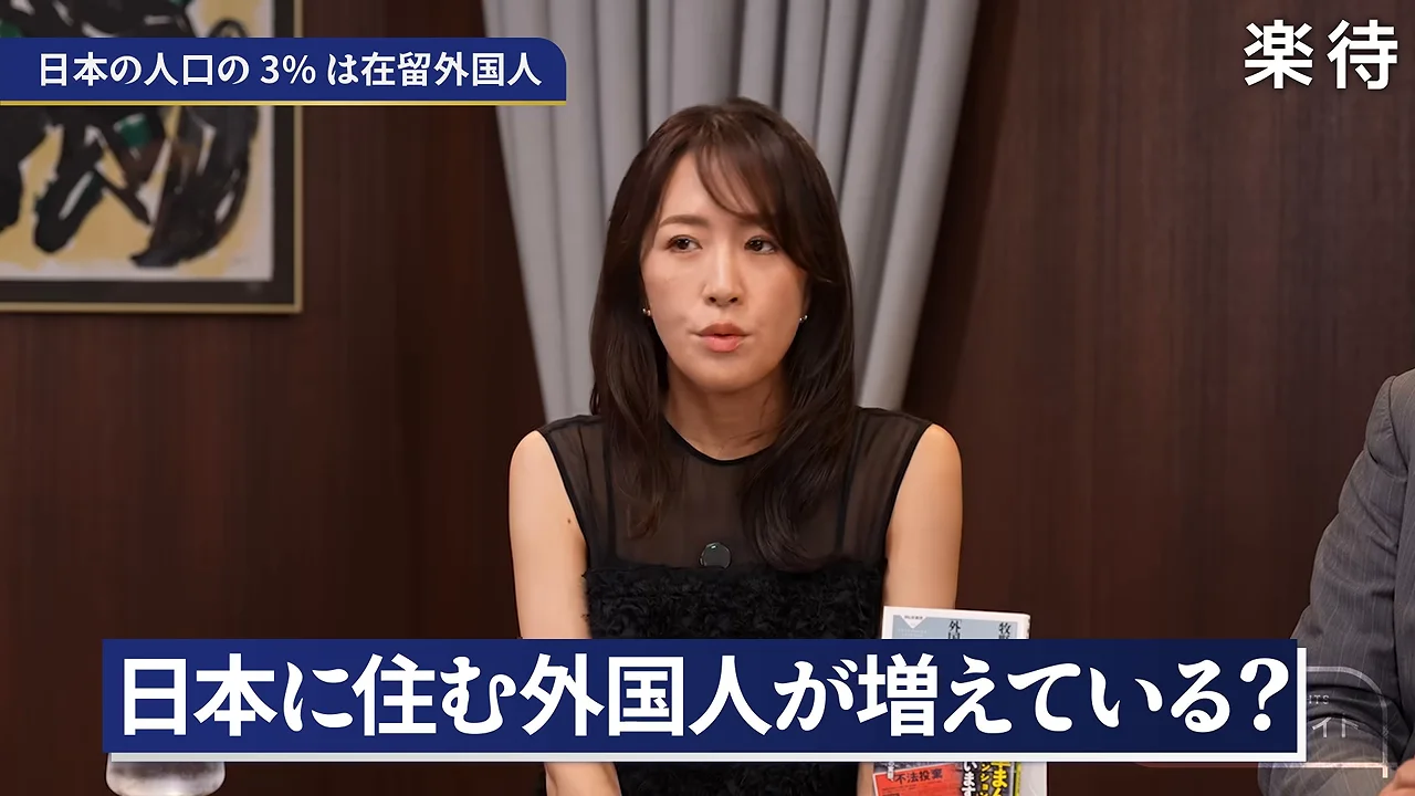 スタジオで黒い服を着た女性が前を見つめている様子。