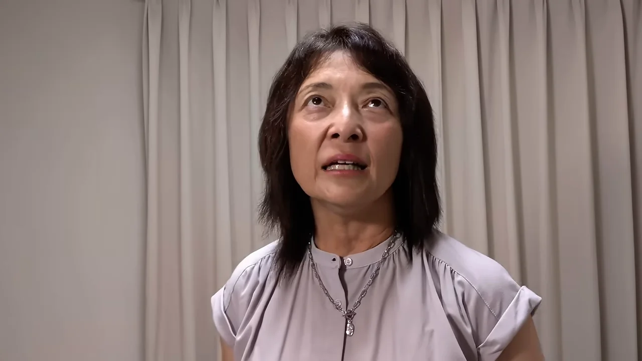 視線を斜め上に向けて落ち着いた表情で話す女性。