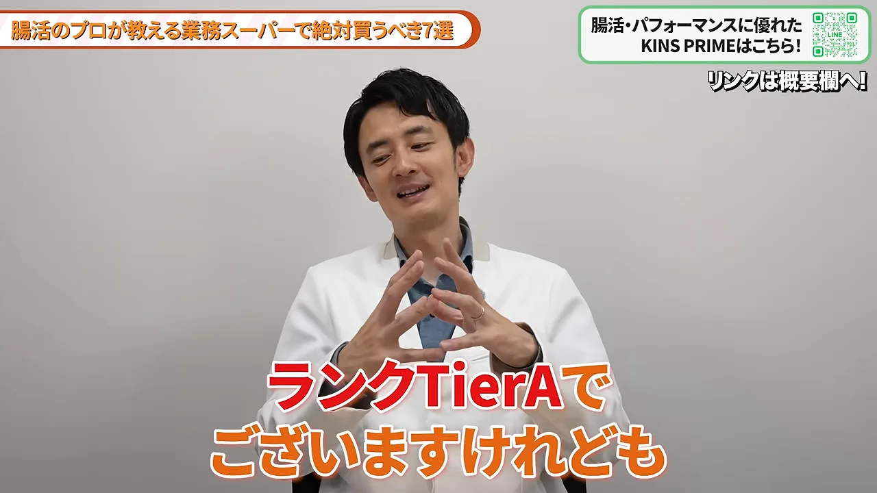白衣を着た男性が両手を組んでカメラに向かって話している様子