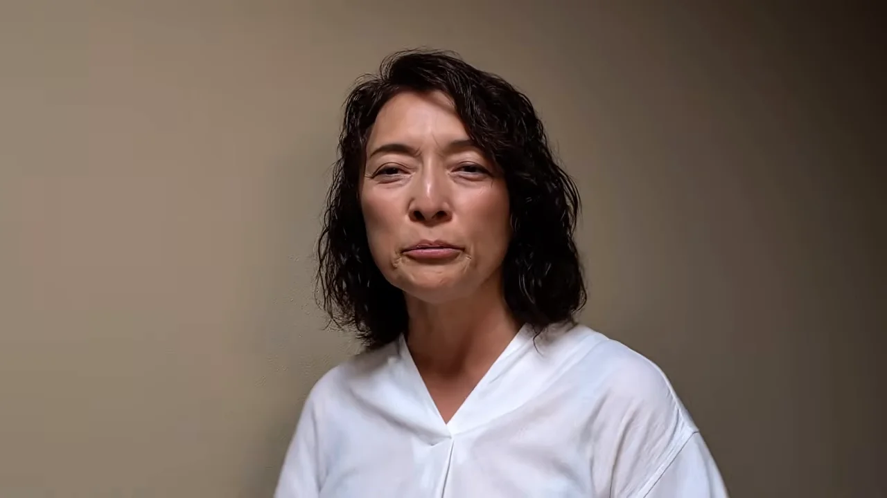女性がカメラを見つめながら口元を結んでいます。