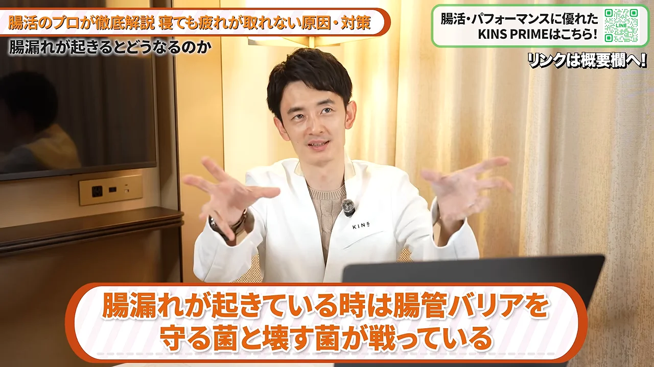 白衣を着用した男性が両手を前に差し出して解説している様子。