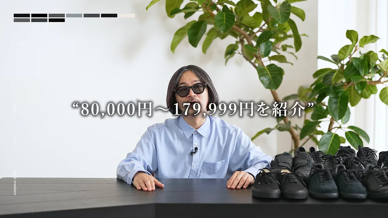 テーブルに黒いスニーカーが並び、サングラスをかけた男性が手を置いて座っています。
