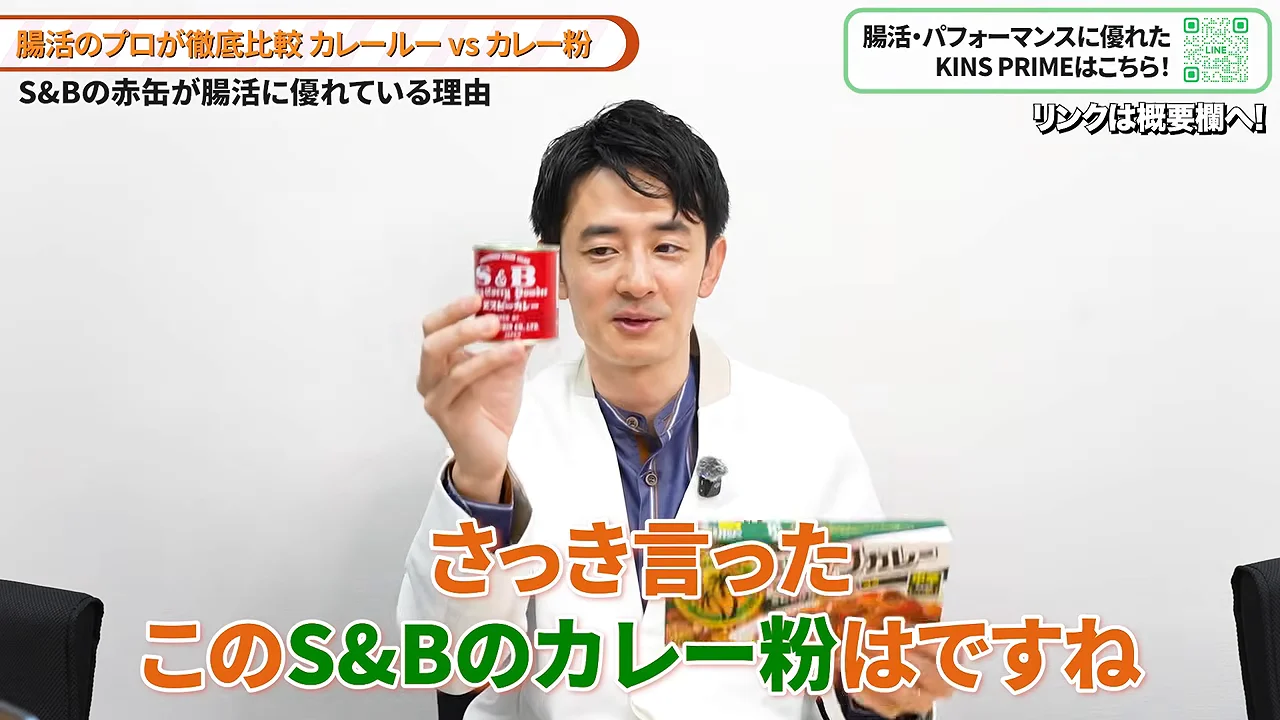 白衣を着た男性がカレー粉の缶とカレールーの箱を手に持ち説明しています。
