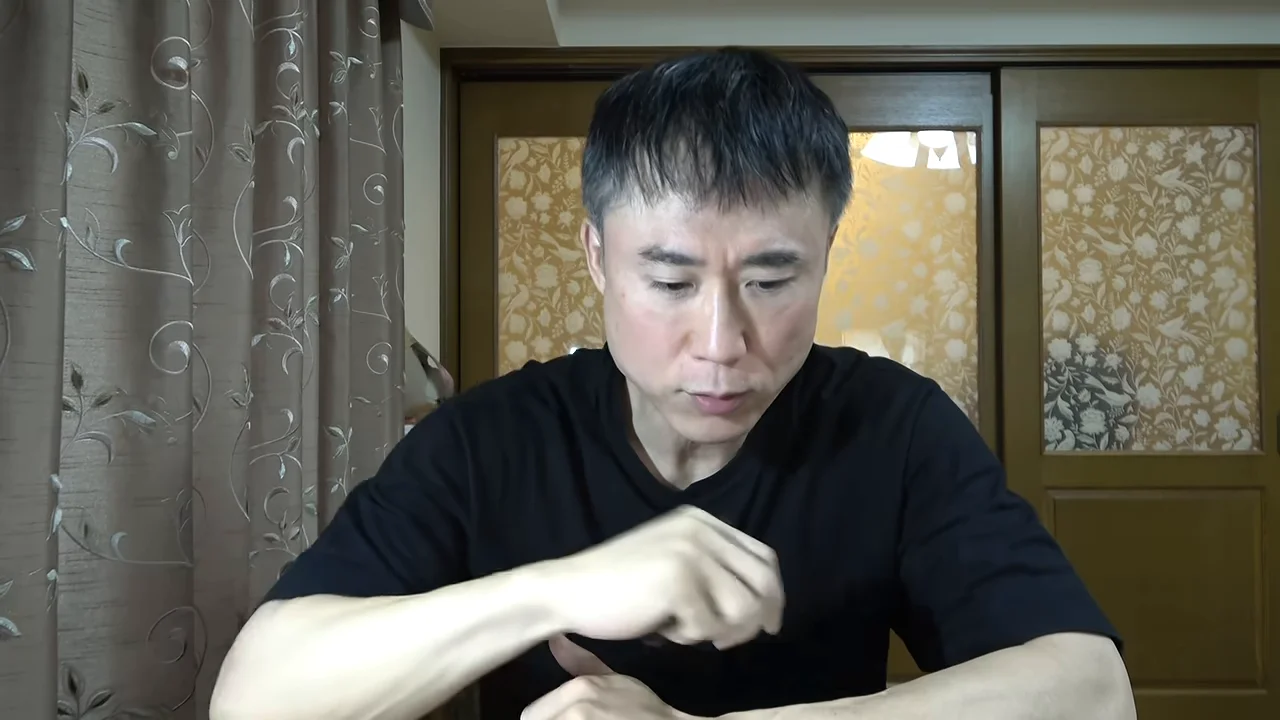 男性が室内で前かがみになり、手元を見つめながら話しています。