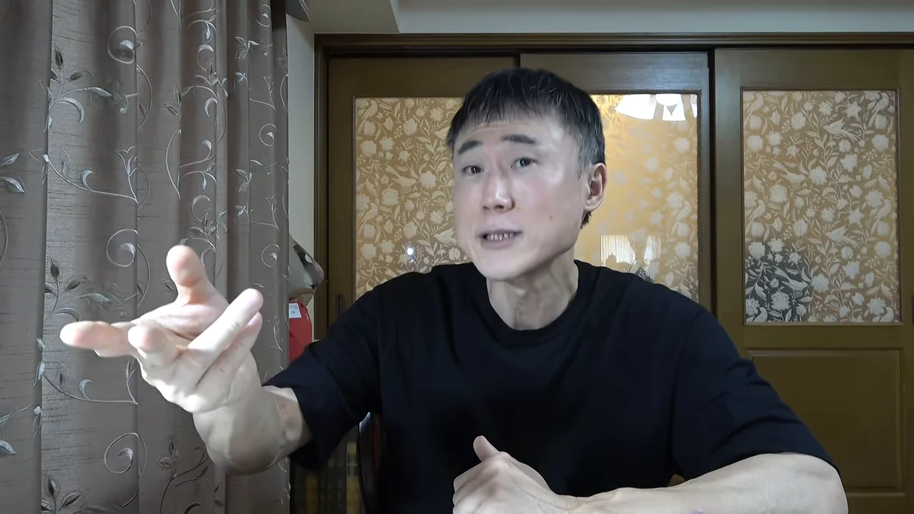 黒いシャツを着た男性が身振りを交えながらカメラに向かって語りかけています。