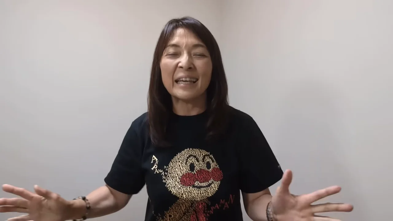 黒いTシャツを着た女性が両手を広げて身振り手振りを交えながら話している様子