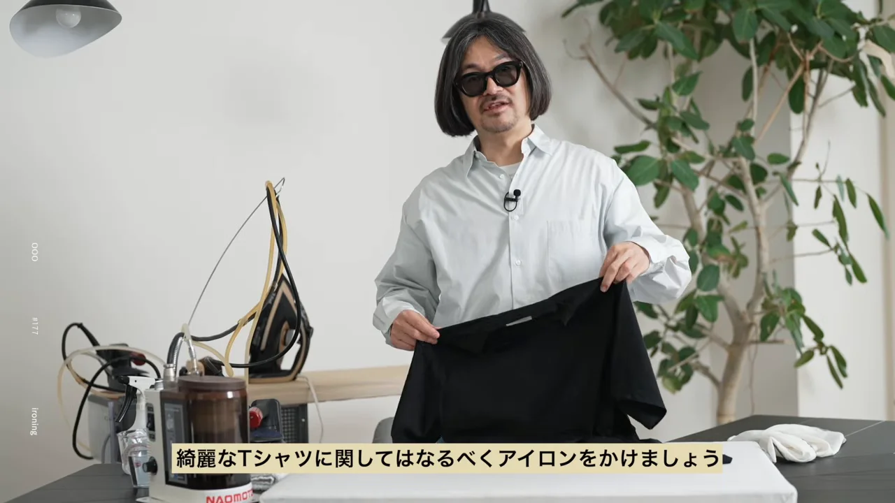 男性が黒いTシャツを両手で広げて見せています。