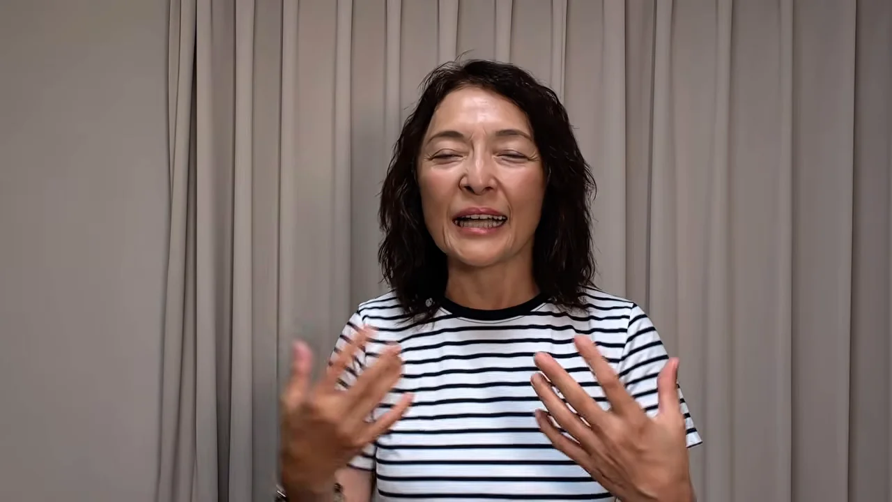 ボーダー柄の服を着た女性が身振りを交えながら話している様子。