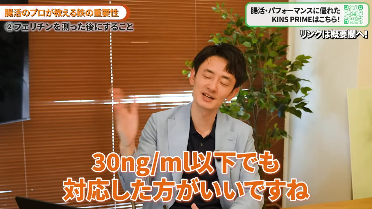 水色のジャケットを着た男性が手を挙げて笑顔で話している場面
