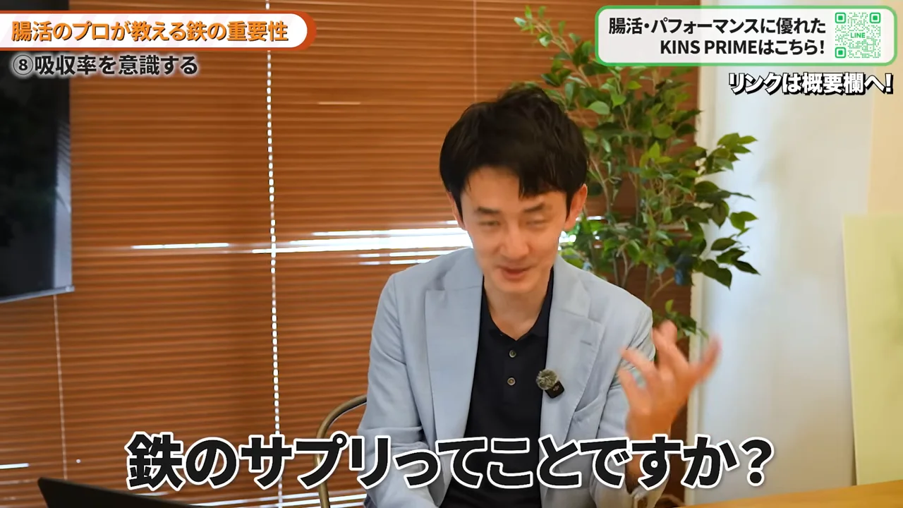 水色のジャケットを着た男性が身振りを交えて語っている場面